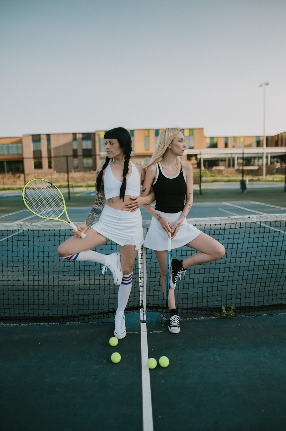 Two women in athletic wear play tennis on a court with rackets.
